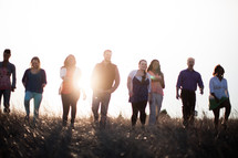 group of people walking outdoors in a field at sunset 