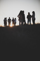 groups gathering outdoors talking at sunset 