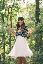 An African-American woman standing in a forest twirling in a skirt 