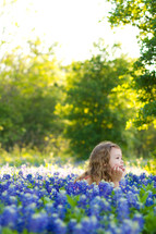 little girl lying in a field of blue bonnet flowers