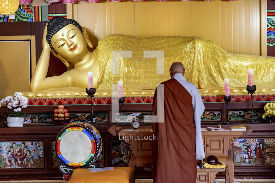 A Buddhist monk offering prayers to a lying Buddha