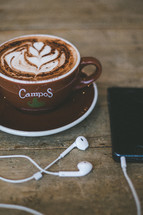 cup of cappuccino and earbuds 