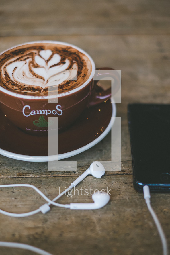 cup of cappuccino and earbuds 