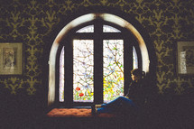 A woman sitting in a window thinking. 