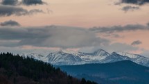 Panoramic view of colorful evening sky over snowy alpine mountains Time lapse
