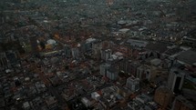 Aerial drone shot over Cityscape of Quito City after sunset time behind mountains - Skyline with high-rise buildings and lighting roads in capital of Ecuador - Tilt up