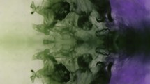 Vertical View Of Ink Visuals With Green And Purple Color Blending Under Water. Slow Motion	