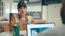 Young beautiful business lady discussing plans with colleague and sharing papers with him during meeting in the office. Over the shoulder shot
