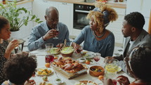 Black family having food and drinks at kitchen table, smiling and discussing something during home dinner. High angle view
