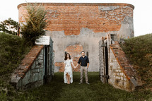 a couple standing in front of a brick building holding hands 