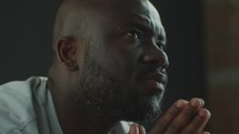 Black Man Holding Palms Together and Whispering a Prayer
