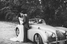 bride and groom kissing in front of an old car 