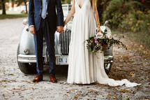 bride and groom standing in front of an old car 