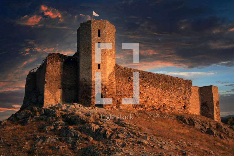 Fortress on the mountain with flag at twilight. Biblical concept of the tower of escape.
