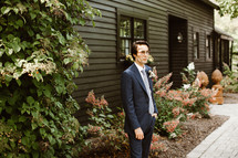groom standing outdoors in front of a house 