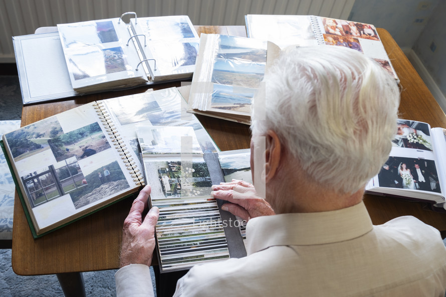 Top view of a senior man looking through old photo albums themes of memories nostalgia photos retired	