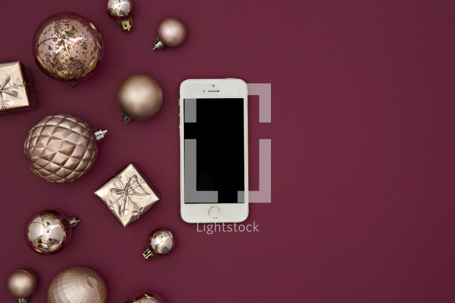 cellphone and gold ornaments on berry red
