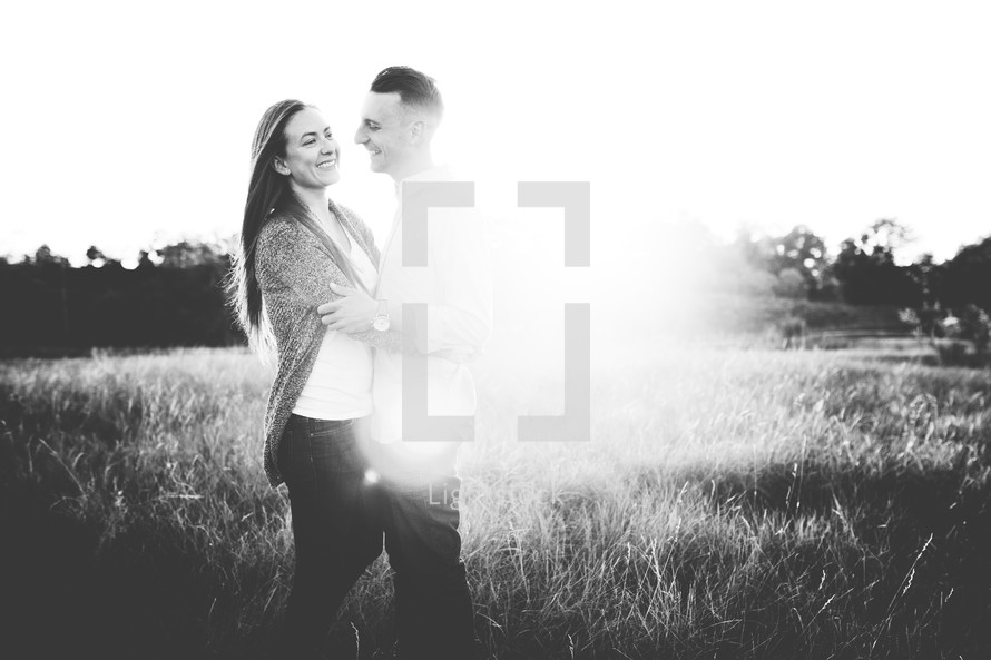 a couple standing together hugging in a field 