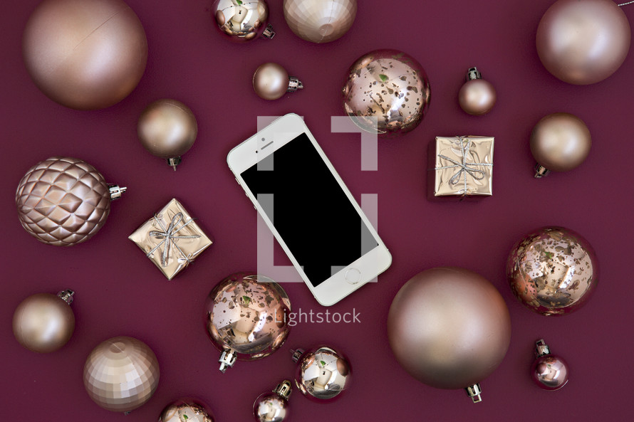 cellphone and gold Christmas ornaments on red 