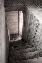 Dirty old downward wooden cellar stairway in black and white