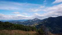 Mountain scenery in the national park, forests and
 dominant rocky peak. Fluffy clouds in the blue sky. timelapse video