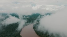 Drone view from clouds of a river in a tropical rainforest.