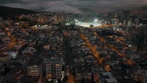 Dusk drone riser reveals vast illuminated Quito city and sport stadium	