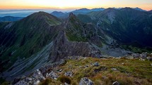 Sunset in the rocky alpine mountains, the sun illuminates the mountain ridge, timelapse