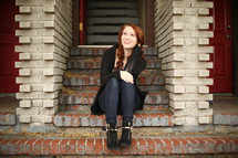 a teen girl sitting on brick stairs 