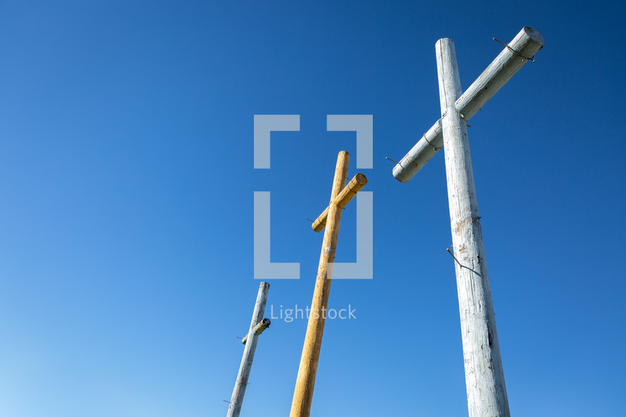 Three wooden crosses nails against bright blue sky