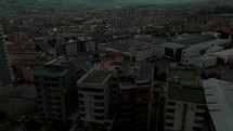 Cinematic aerial tilt up shot over residential area of Quito city at dusk with mountain range in background	