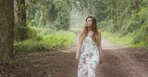 Young beautiful woman with a white dress walking in a green forest