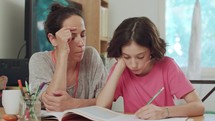 Mother helping her daughter to prepare homework at home