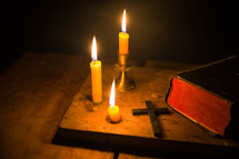 Bibles on a dark background lit up by a candle