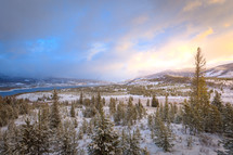 Rocky Mountains Colorado landscape with melting snow and evergreen trees near water at sunset 