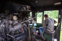 Man in control area of old steam train locomotive