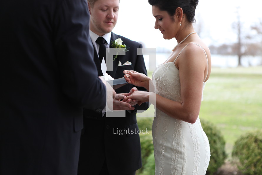 groom putting a ring on his bride finger