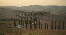 villa at sunset with cypresses in the tuscan hills