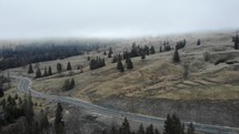 Aerial shot of a highway by the sloping mountains on a misty morning.