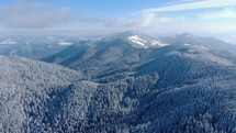 Aerial Panoramic View Of Snow Covered Trees On Mountains During Winter - drone shot