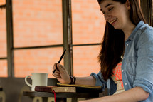 young woman reading a Bible and journaling 