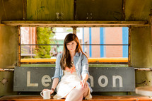 a woman sitting on a bench with a coffee 