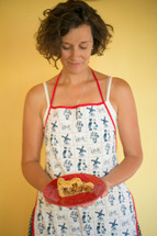 woman in an apron holding a slice of pie