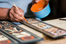 a man painting carved wood 