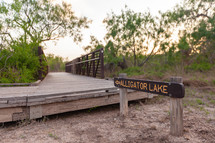Sign pointing towards Alligator Lake at boardwalk bridge entrance in Estero Llano Grande State Park
