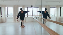 Young ballet duet practicing synchronic moves in modern spacious dance studio with mirror wall. Full shot, copy space
