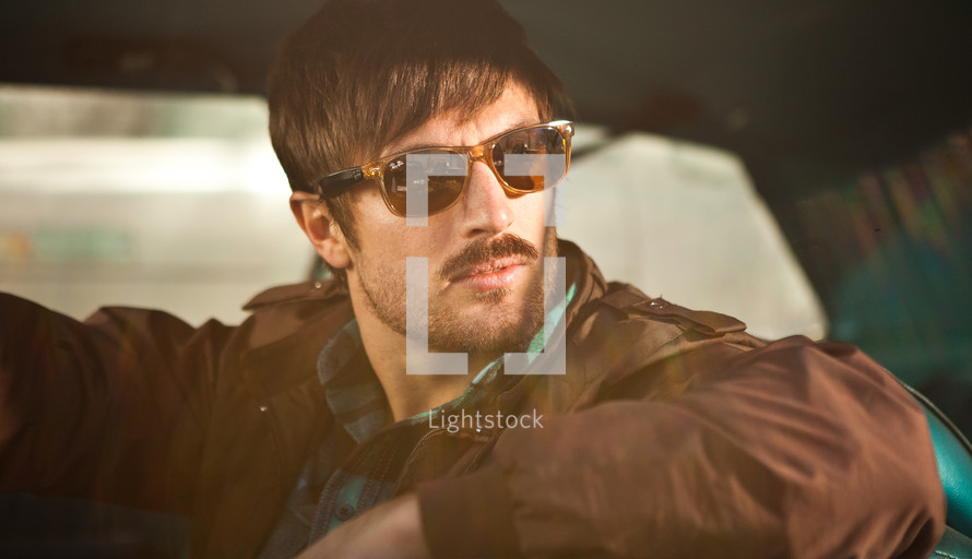 man looking out a car window wearing sunglasses