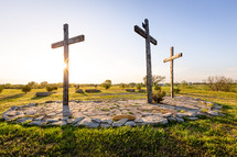 Three wooden crucifix crosses on stone and grass 