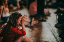 a woman sitting and praying during a worship service 