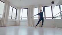 Young professional male dancer practicing ballet pirouettes alone in the studio. Zoom shot, low angle view
